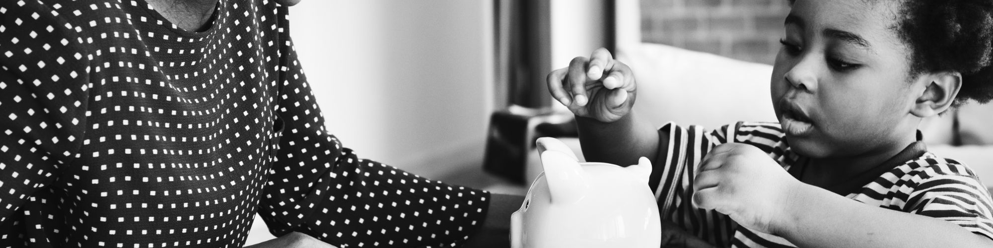 woman helps little boy put money in piggy bank